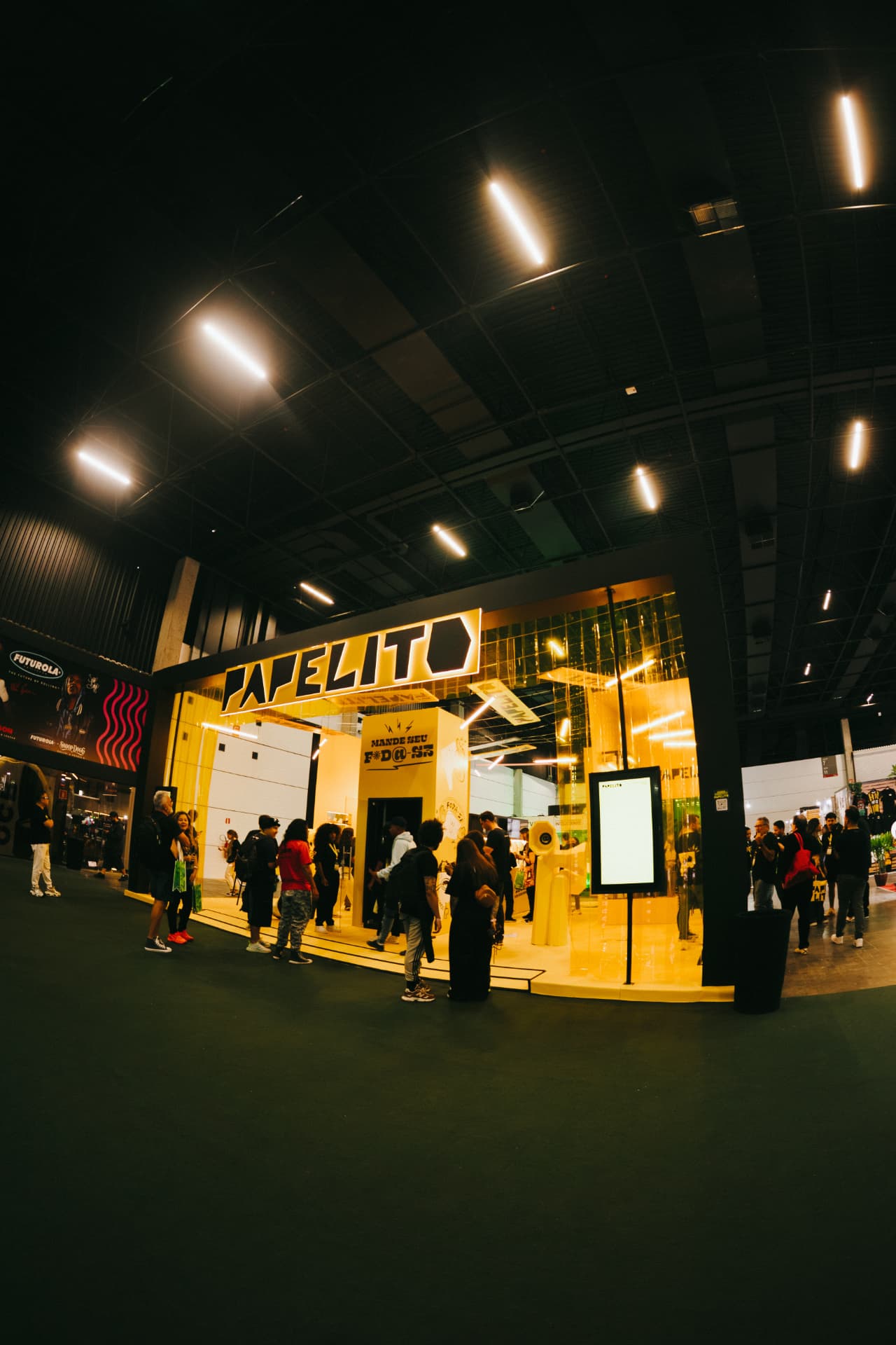 Estande amarelo da Papelito cheio de visitantes na feira